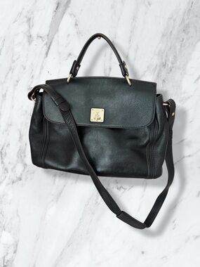 MCM black pebbled leather flap medium top handle bag with a shoulder strap.